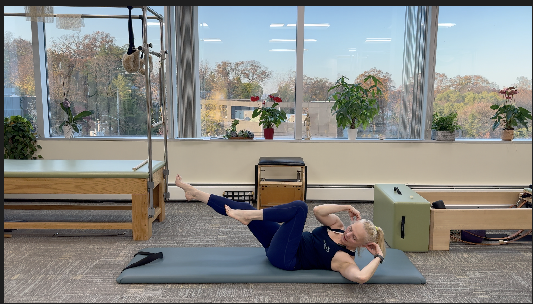 a woman performing Elbow To Knee Pilates exercise